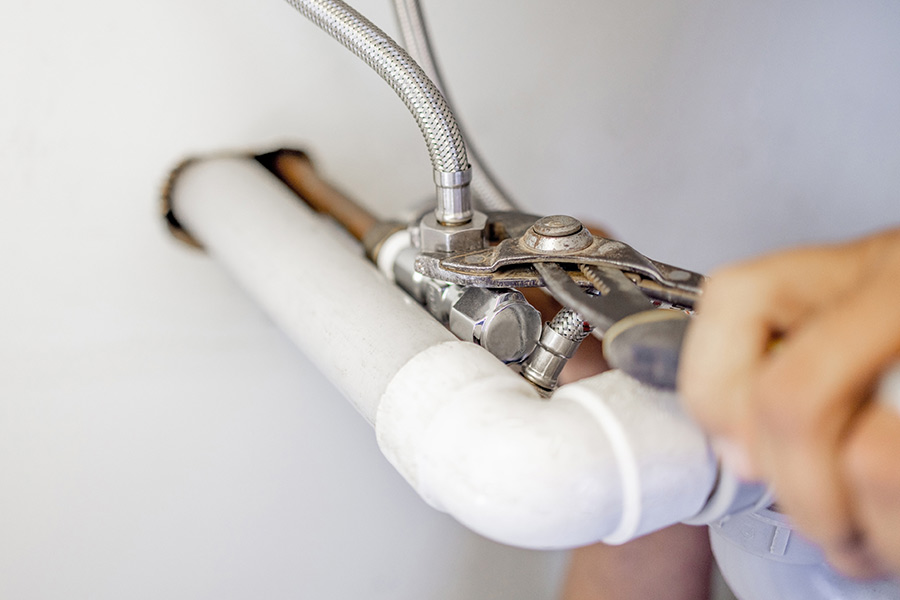 Plumber tightening pipe under sink